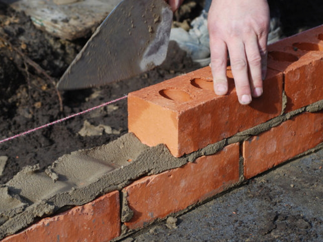 Bricklayer laying a course of bricks