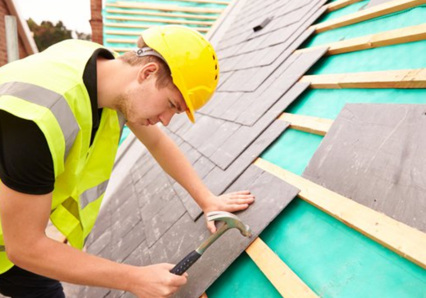 Professional roofer tiling a slate roof