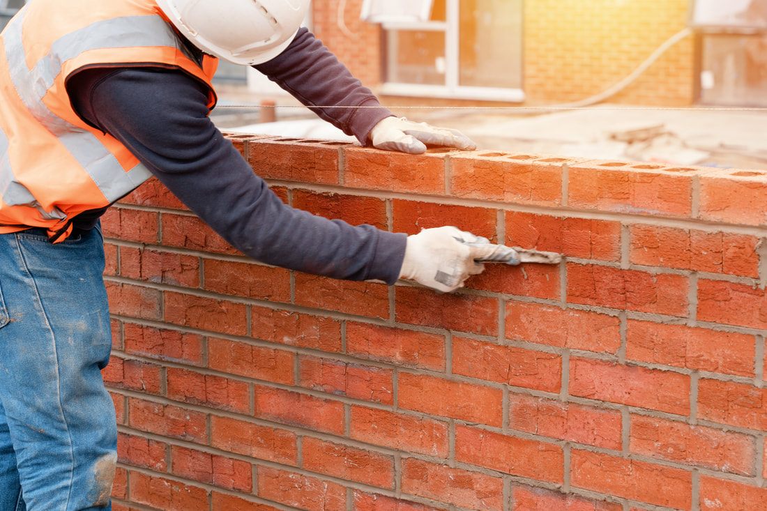 Bricklayer laying a course of bricks